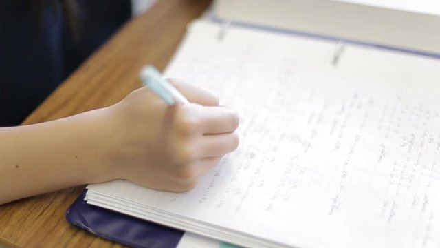 Student writes work in notebook