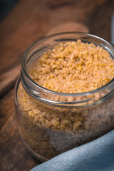 Grain bulgur in a glass jar and a spoon on the table