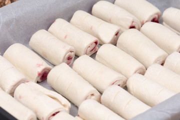 Fototapeta na wymiar Raw puff pastry stuffed with cherry cream on the baking tray