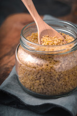 Grain bulgur in a glass jar and in a spoon on the napkin