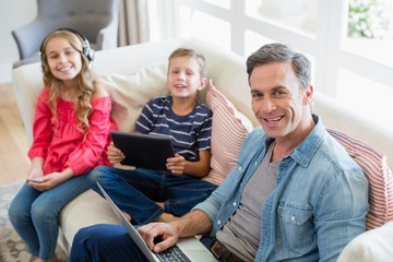 Portrait of father and kids using laptop and tablet 