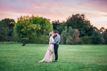 Fototapeta premium Two lovers in a field at sunset. A bearded man and a pretty girl.