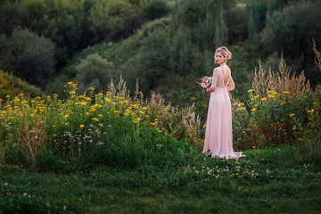Bride in pink dress with bouquet in hands.
