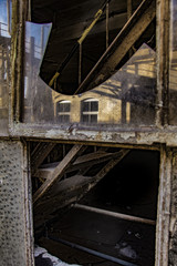 Stairs behind the broken window of an old factory