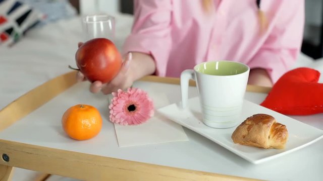 Girl having a breakfast in bed and drinking tea, steadycam shot
