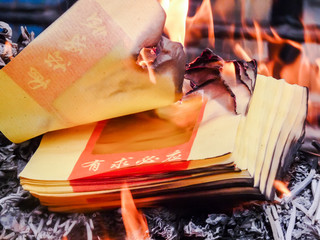 Naklejka na ściany i meble Burning Chinese joss paper or ghost money at a temple during Chi