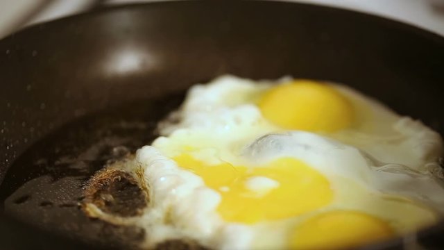 Close up refocusing shot of Preparing scrambled eggs on hot frying pan