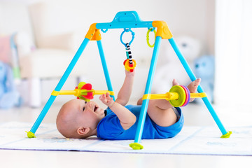 Baby boy on play mat. Child playing in gym.