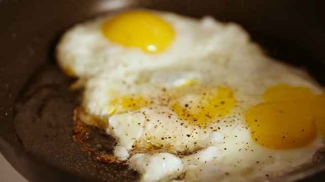 Close up shot of cooking fried eggs with spice in frying pan for breakfast