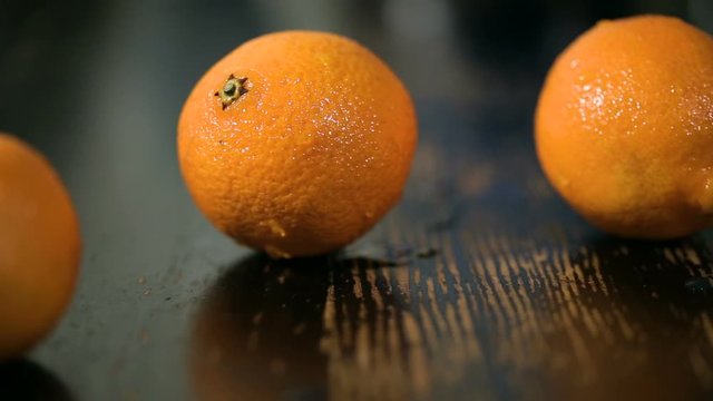 sliding shot of organic tangerines on black wood table. Orange fruit on a wooden background