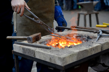 The smith keeps nippers a metal detail in a forge brazier