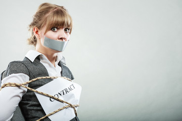 Businesswoman bound by contract with taped mouth.