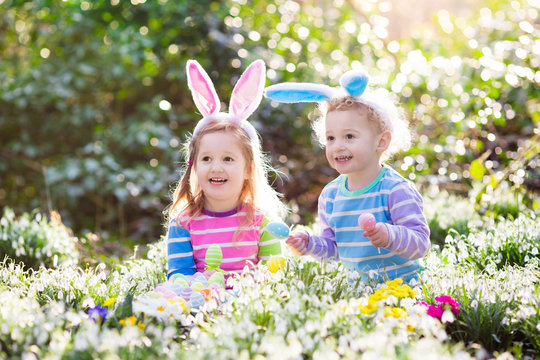 Kids on Easter egg hunt in blooming spring garden