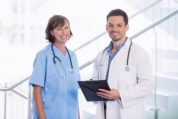 Nurse and doctor discussing over clipboard in corridor