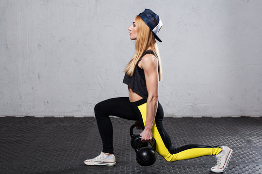 Fitness woman doing lunges with kettlebells in hands