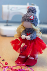 Handmade doll in a red dress and gray hat