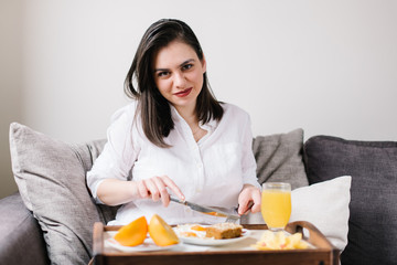 Obraz na płótnie Canvas Beautiful woman eating breakfast on the couch