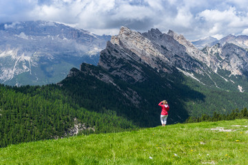Fototapeta na wymiar Hiker Girl in Red on the Mountain Valley Looking Forwards