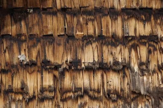 Sonnenverbrannte Holz-Schindeln an Hauswand