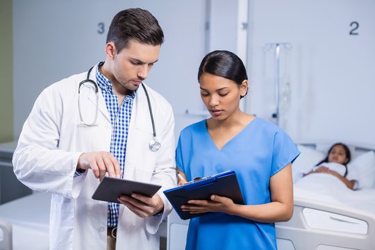 Doctor and nurse using digital tablet and clipboard