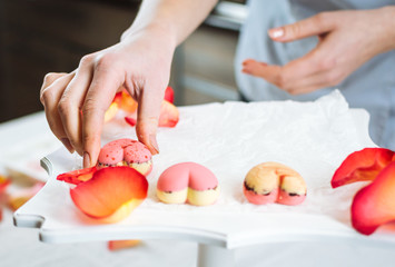 Pastry-cook puts prepared candies in the form of hearts on tray
