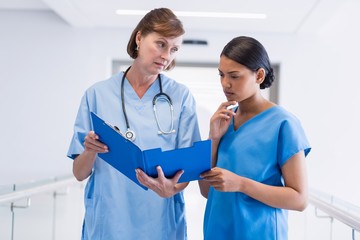 Nurse and doctor discussing over clipboard