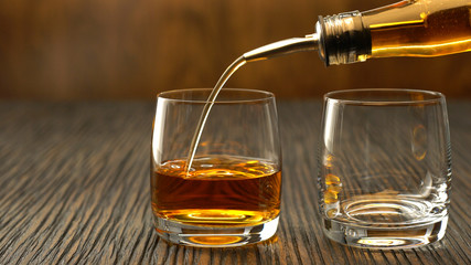 Pouring whiskey into the glass on a wooden table