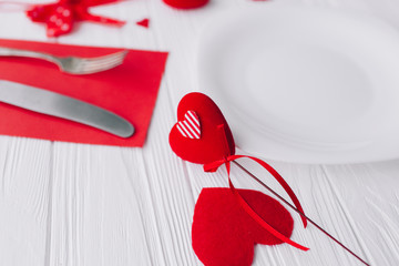 valentines day.plate ,cutlery ,knife,fork,red hearts on white wooden background 