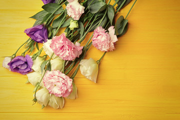 Bouquet of eustoma flowers on yellow wooden background