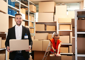 Young businessman holding box at warehouse