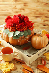 Beautiful autumn composition of red flowers, berries and pumpkin on wooden background