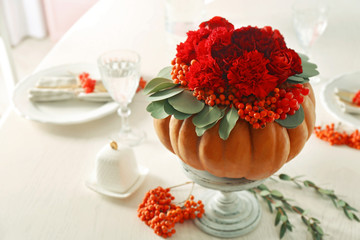 Beautiful composition of red flowers, berries and pumpkin on white stand