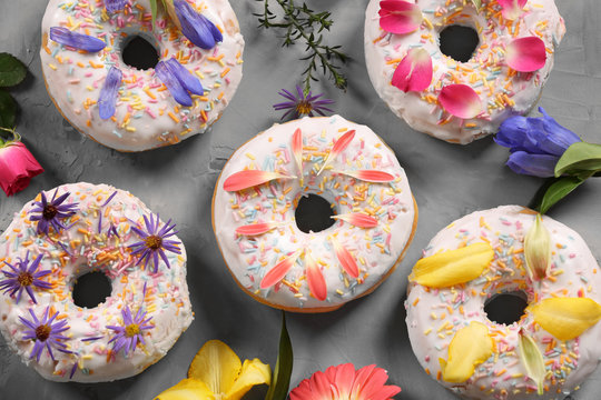 Delicious donuts and flowers on grey textured background