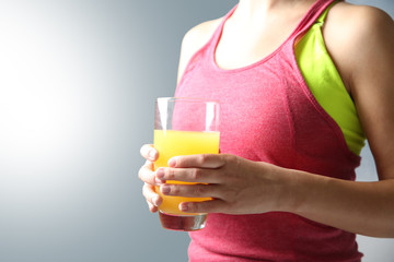 Closeup of sporty woman holding glass of orange juice