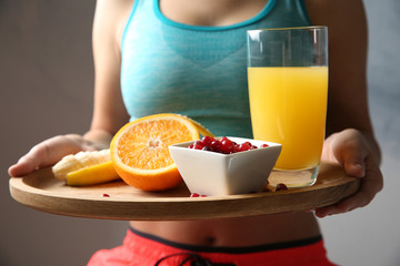 Closeup of sporty woman holding wooden tray with healthy breakfast
