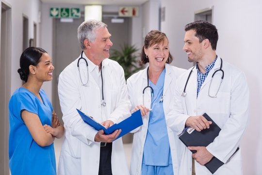 Smiling nurse and doctors discussing over clipboard