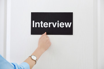 Female hand knocking on door with black signboard