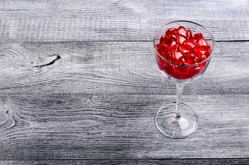 Gray wooden boards background with a glass filled with red hearts