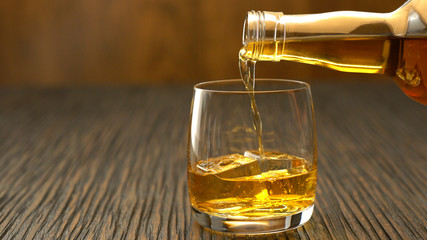Pouring whiskey into the glass on a wooden table
