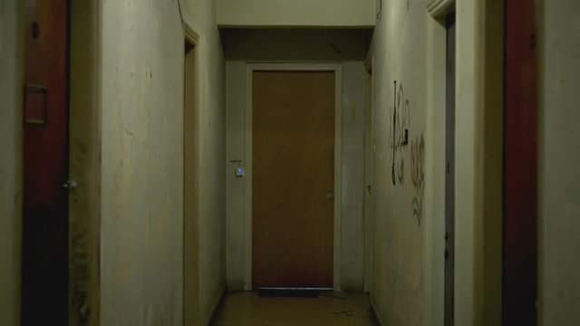 Walking inside a long dark hallway of old apartment building.
