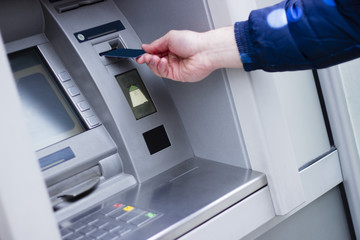 Hand of a man with a credit card, using an ATM. Man using an atm machine with his credit card.