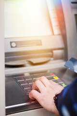 Hand of a man with a credit card, using an ATM. Man using an atm machine with his credit card.