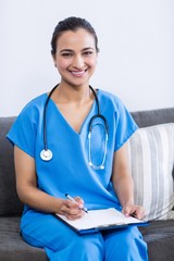 Portrait of female doctor writing on clipboard