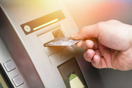 Hand of a man with a credit card, using an ATM. Man using an atm machine with his credit card.