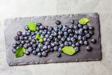 Berry fresh blueberries with mint leaves on black slate board © lblinova