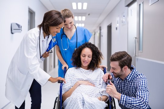 Doctor interacting with pregnant woman in corridor