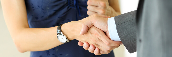Businessman and woman shake hands as hello in office closeup