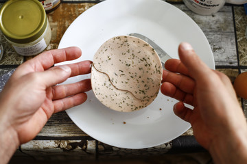 Close-up of men hands eating a half buns with vegetarian sausages with warm colors in soft-focus in the background.