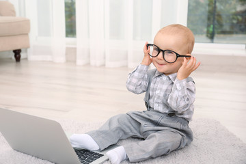 Cute baby boy with laptop on carpet