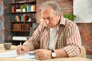 Senior man calculating taxes at home